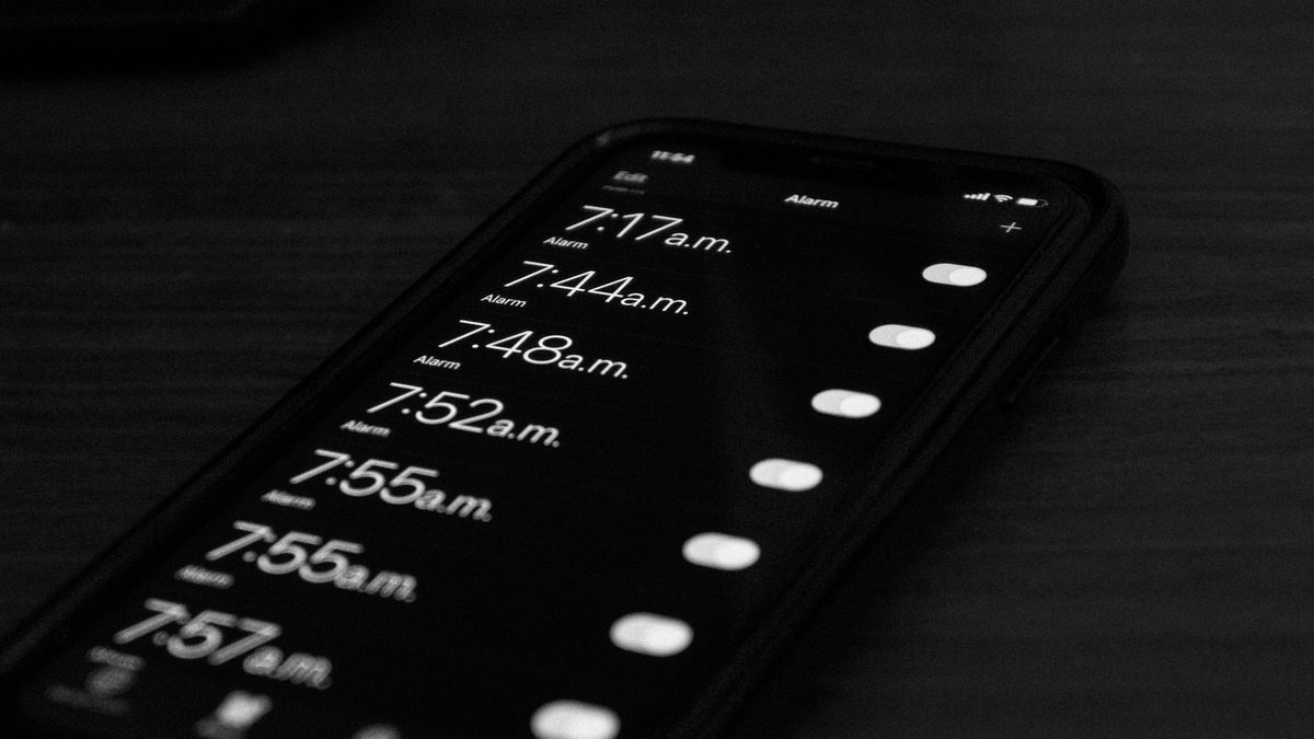 Un iPhone sur une table sombre affichant une longue liste d'alarmes