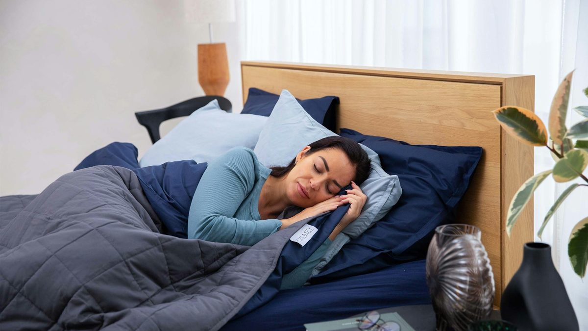A woman sound asleep under a grey duvet in a bright bedroom