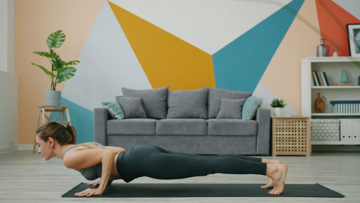 A woman in a push-up position on a yoga mat at home