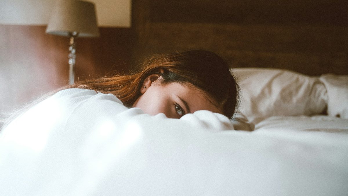 A woman peering out from under the duvet, barely awake