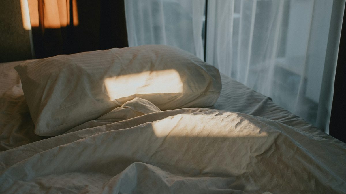 Morning sun falling across a white pillow and duvet